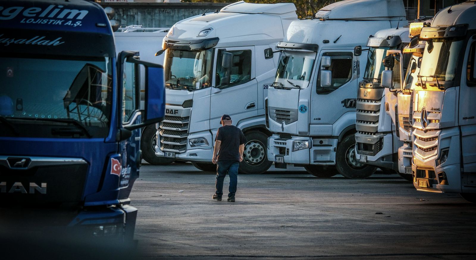Row of European tractor units parked in a commercial yard in low evening light