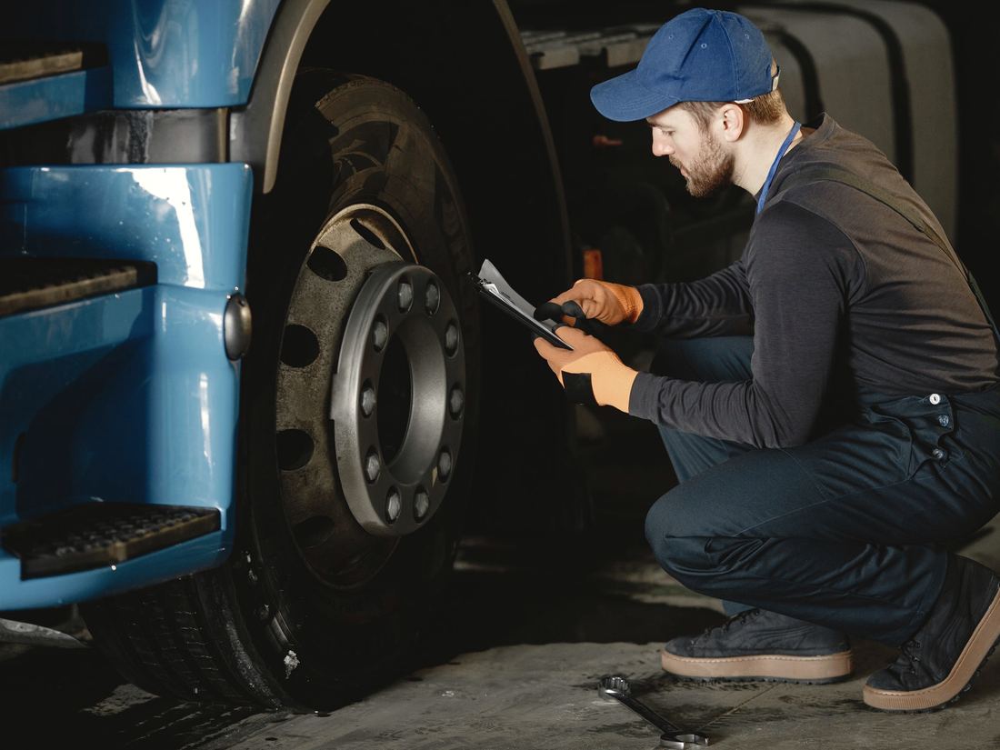 Technician checking the wheel and hub of a truck against a checklist